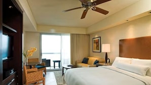 Une chambre d’hôtel équipée d’un lit, d’un bureau, d’une chaise, d’un canapé, d’un ventilateur de plafond et d’une fenêtre.