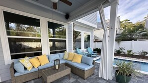 An outdoor patio with a wicker sofa, a wooden coffee table, and a potted plant. - Sea Change Home with Pool, Lake Access & Golf Cart (Santa Rosa Beach)