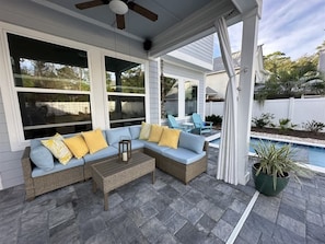 Eine Terrasse im Freien mit einer Rattan-Couch, einem Holztisch und einem Topfpflanzen.