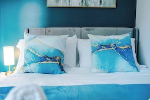 A bed with two pillows, a bedside lamp, and a painting on the wall. - *NEW* Snug 3BR House | FREE Parking | PS4 | Wi-Fi (Greater Manchester)