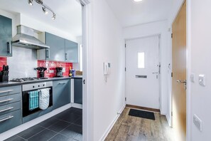 Une cuisine moderne avec des meubles gris, une hotte en acier inoxydable et un sol carrelé de couleur noire.