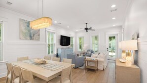 A spacious living area with a dining table, sofas, and a TV mounted on the wall. - Seagrove Home for Groups, Near 30A Beach & Pool (Santa Rosa Beach)