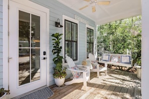 Eine Veranda mit zwei Adirondack-Stühlen, einer Bank und einem Blumentopf.