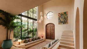A spacious room with a large window, a wooden door, a staircase, and a seating area with cushions. - Rooftop Steam Spa, Private Pool & Jungle Retreat (Tulum)