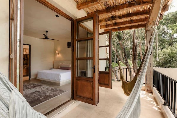 Ein Schlafzimmer mit Bett, Deckenventilator und Blick ins Freie.