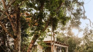 A two-story building with a balcony, surrounded by lush greenery and a stone wall. - Rooftop Steam Spa, Private Pool & Jungle Retreat (Tulum)