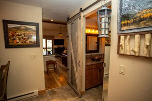 A kitchen with a wooden door, a hanging light fixture, and a framed picture on the wall. - Whetstone Chalet, Golf, Private Lake, XC Ski, Bike trail to Town! (Crested Butte)