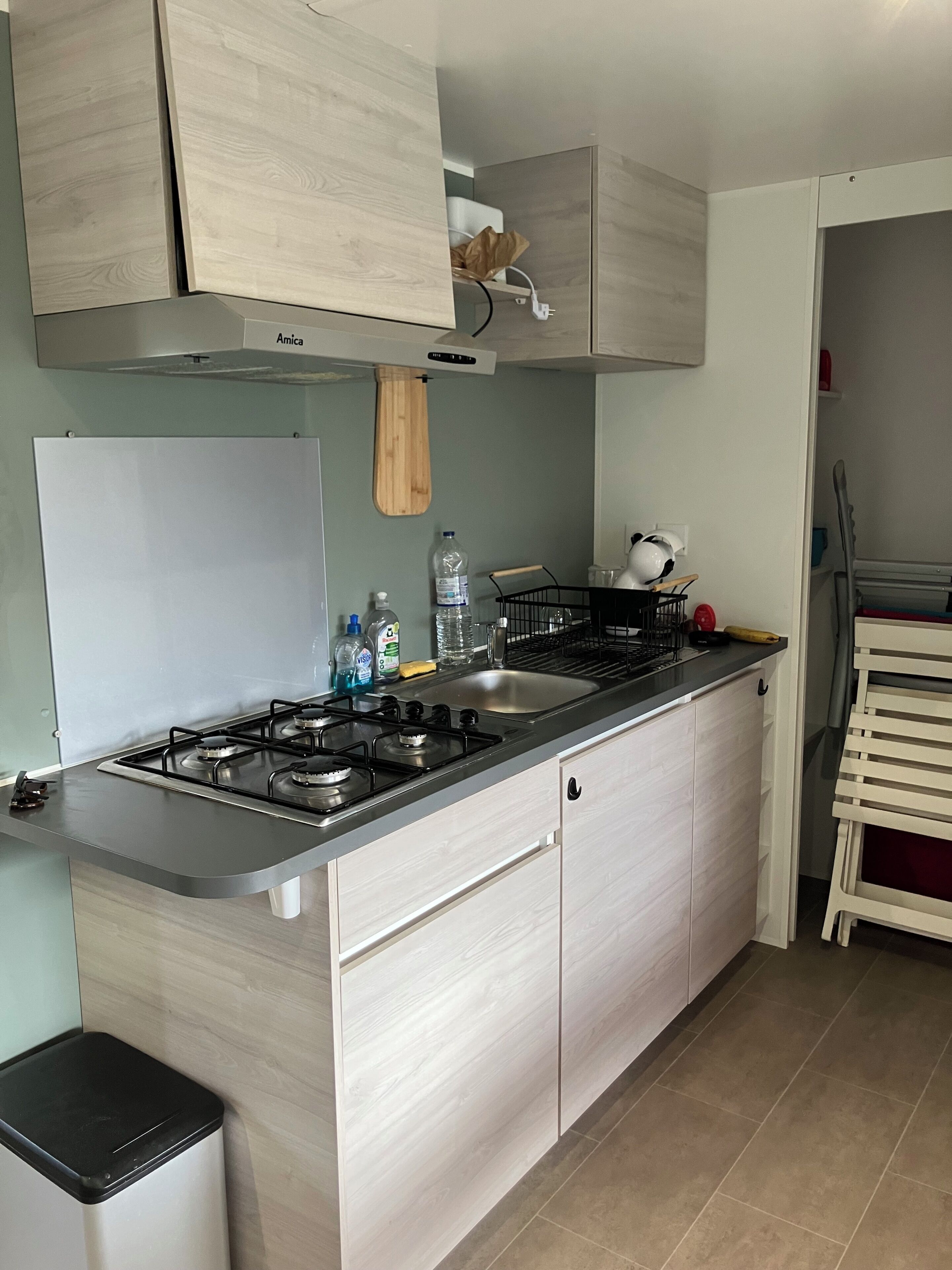 A modern kitchen with light wood cabinets, a stainless steel stove, and a black countertop.