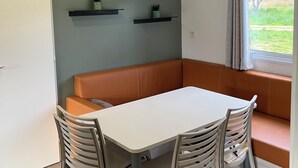 Un intérieur moderne avec une table blanche, deux chaises, un banc marron et deux étagères murales ornées de plantes.