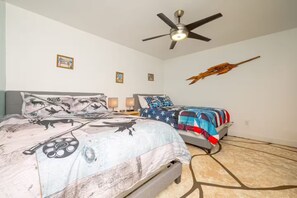 Un dormitorio con dos camas, ventilador de techo y decoración en las paredes.