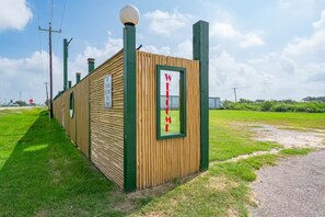 A small wooden structure with a 'WELCOME' sign, surrounded by a grassy area and utility poles.