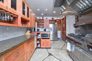 Una cocina con armarios de madera, microondas, refrigerador y estufa a gas.