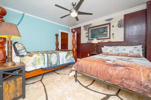 A bedroom with a bed, a nightstand, a lamp, a ceiling fan, and a window with a cityscape view.