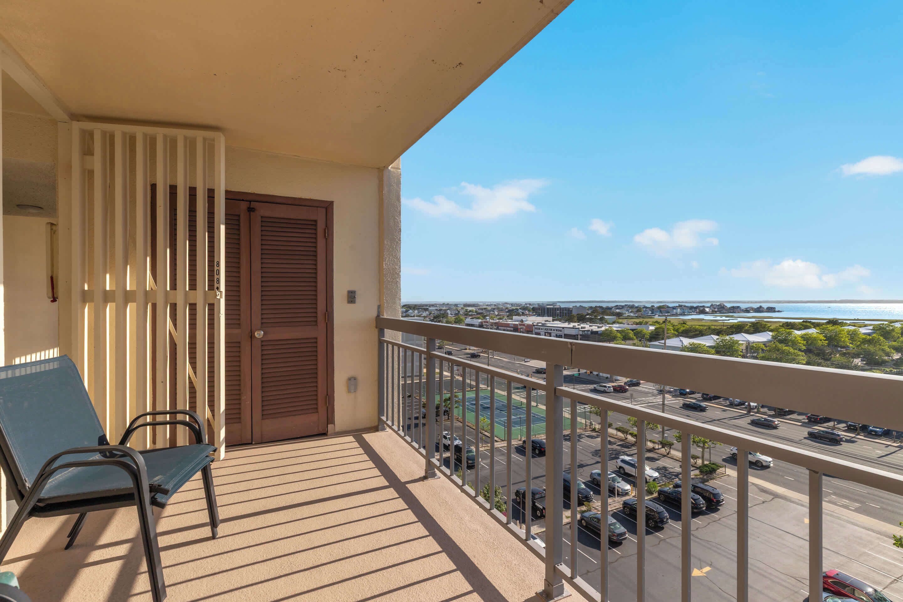 A balcony with a view of a parking lot and a distant body of water.