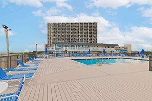 Ein Poolbereich mit Liegestühlen und einem Schwimmbecken, umgeben von einem Hochhaus.