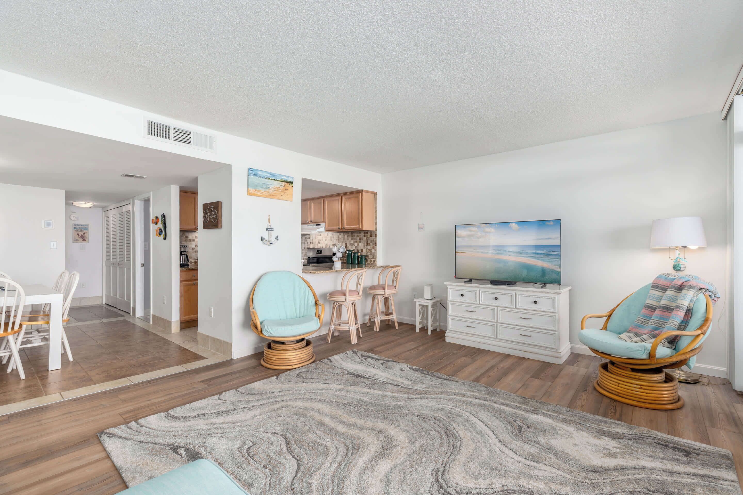 A modern living room with a dining area, kitchen, and a large painting on the wall.