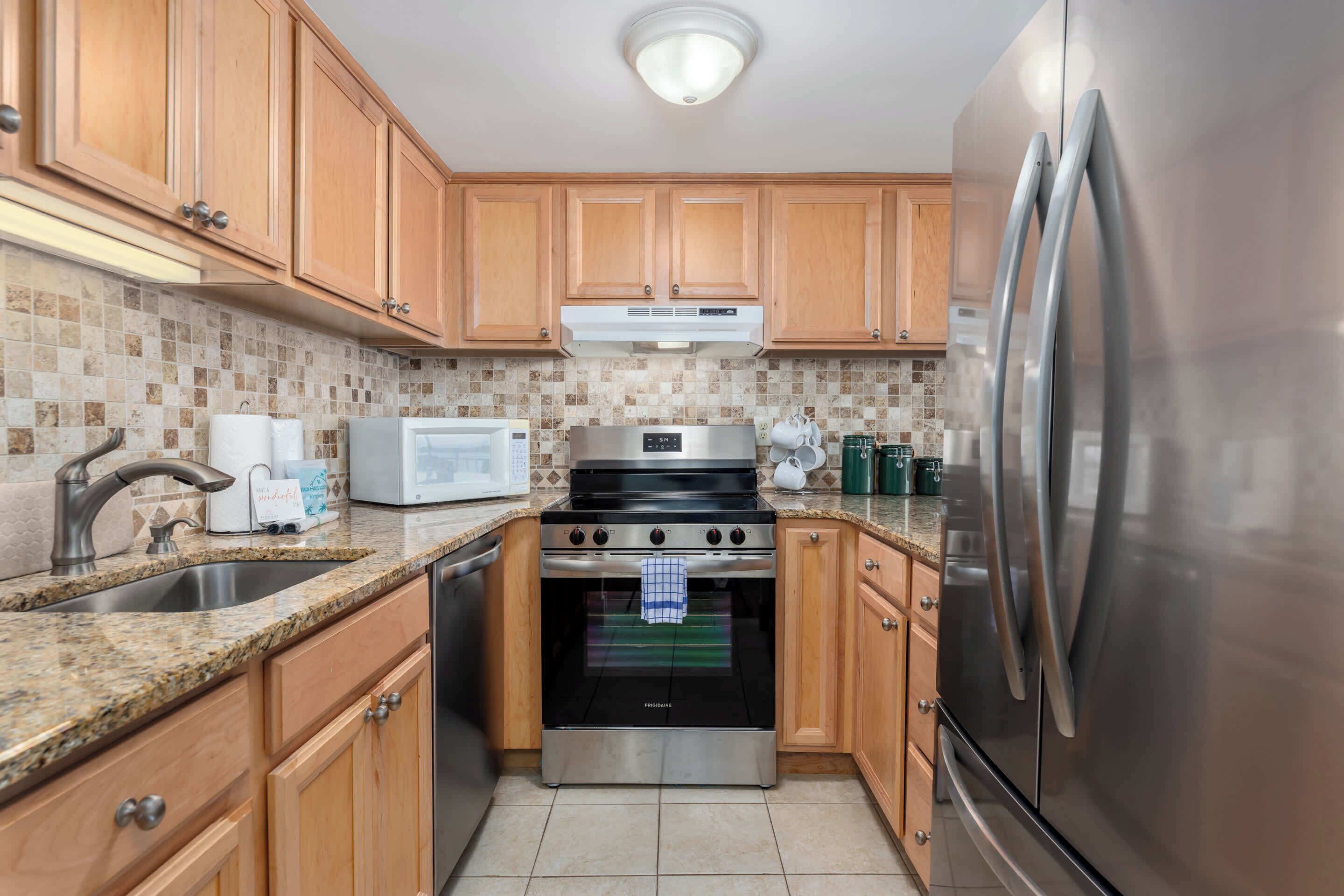 A kitchen with wooden cabinets, a stainless steel refrigerator, a microwave, and a stove.