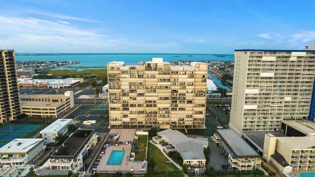 Ein mehrstöckiges Hotel mit Pool, umgeben von anderen Gebäuden und Blick aufs Meer.