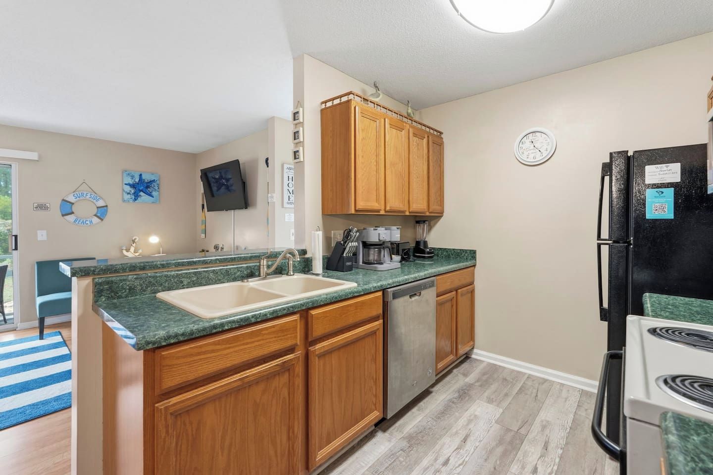 A kitchen with wooden cabinets, a double sink, a coffee maker, and a refrigerator.
