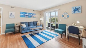 Ein Wohnzimmer mit Sofa, Sesseln, Couchtisch, Teppich und Kunstwerken an den Wänden.