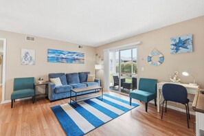 Ein Wohnzimmer mit Sofa, Sesseln, Couchtisch, Teppich und Kunstwerken an den Wänden.