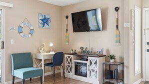 Ein Wohnzimmer mit Fernseher, einem Schild für einen Strandabschnitt und einem Stand-Up-Paddleboard.