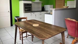 Eine Küche mit einem Holztisch, Stühlen, einer Uhr und einem roten Sessel.