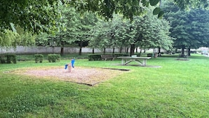 Ein Park mit Spielplatz, Bänken und Picknicktischen.