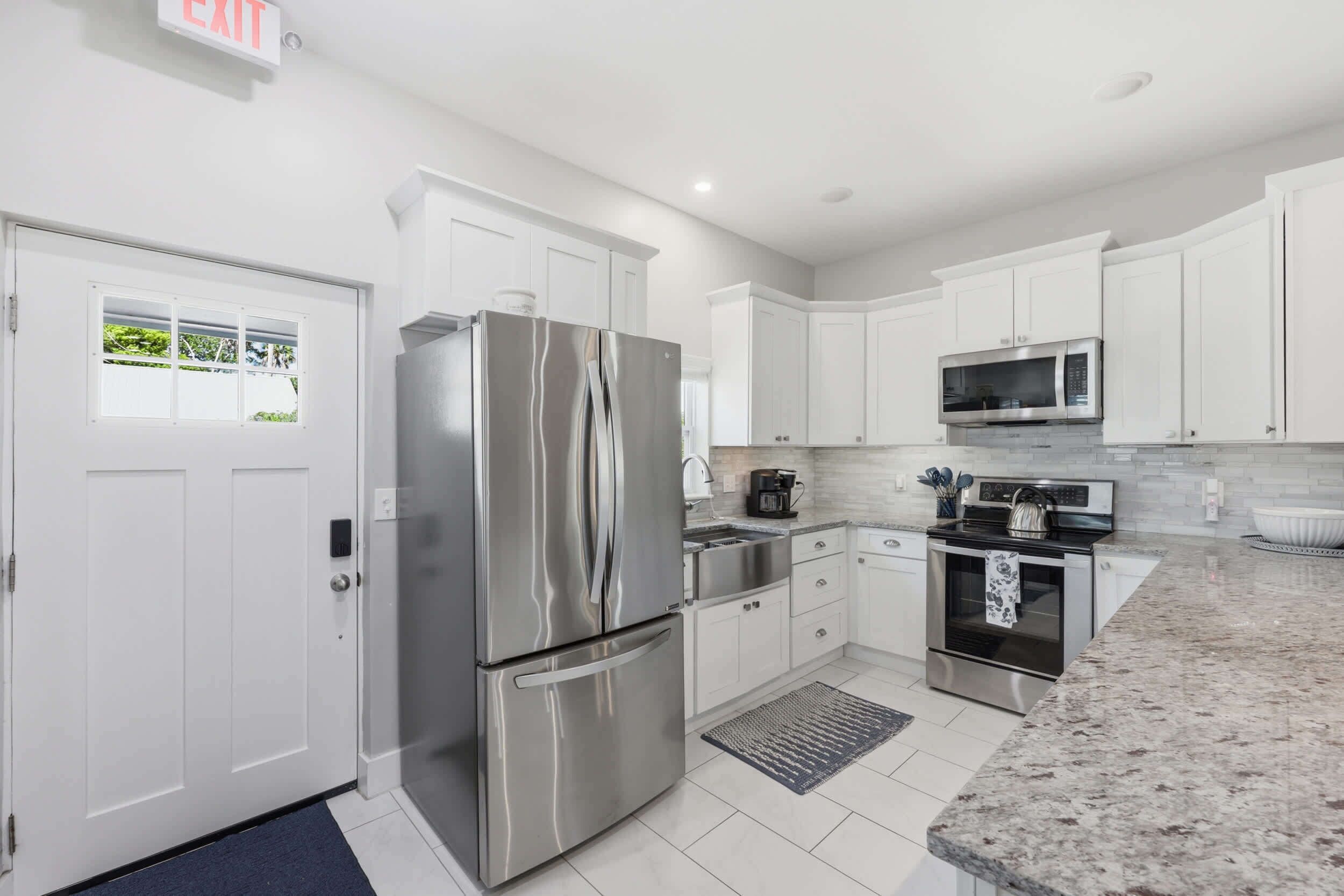 A modern kitchen with white cabinets, stainless steel appliances, a microwave, and a coffee maker.