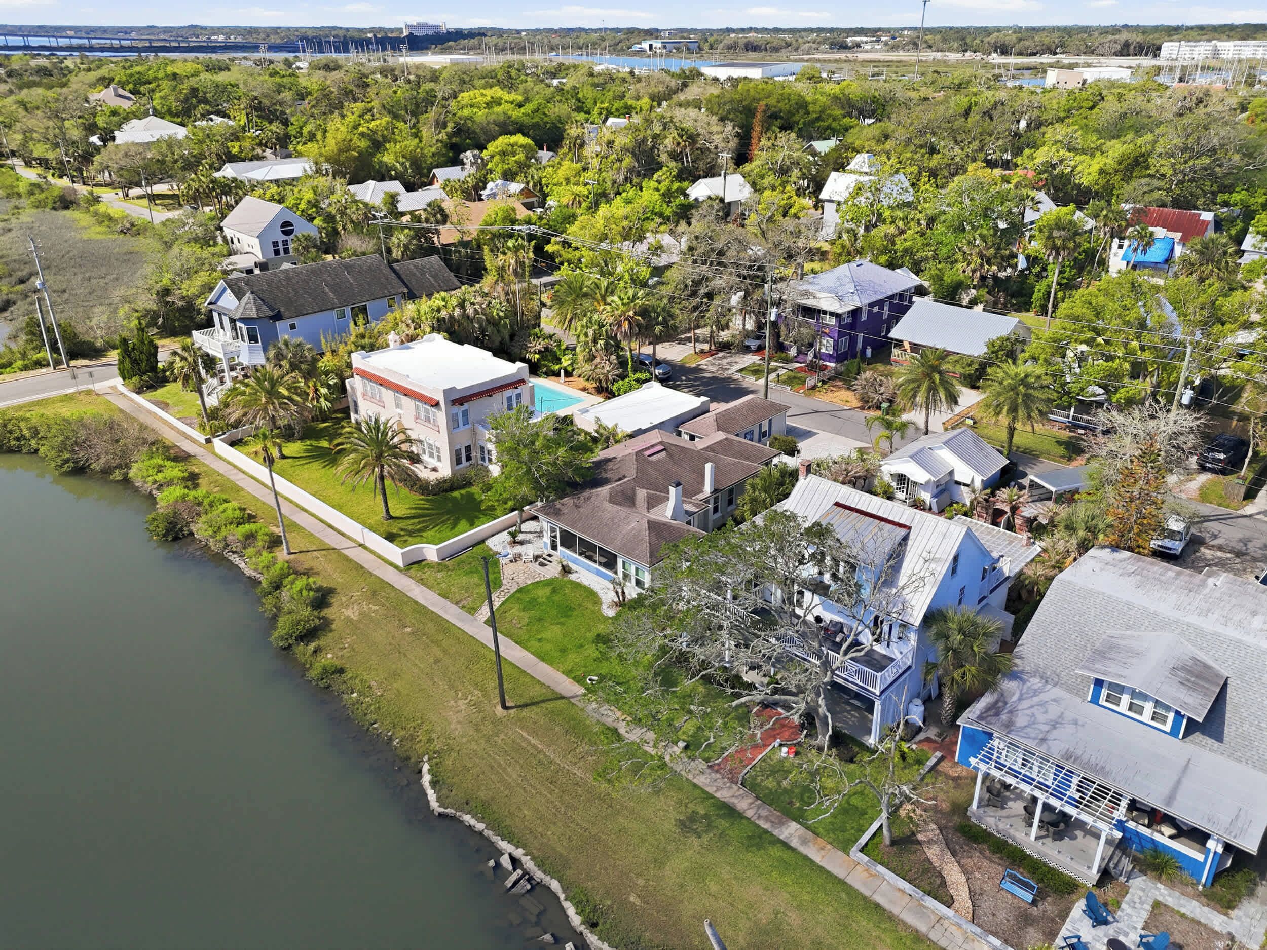 An aerial view of a residential area with houses, a body of water, and a bridge in the background.