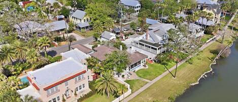 An aerial view of a residential area with houses, a river, and a well-maintained lawn.