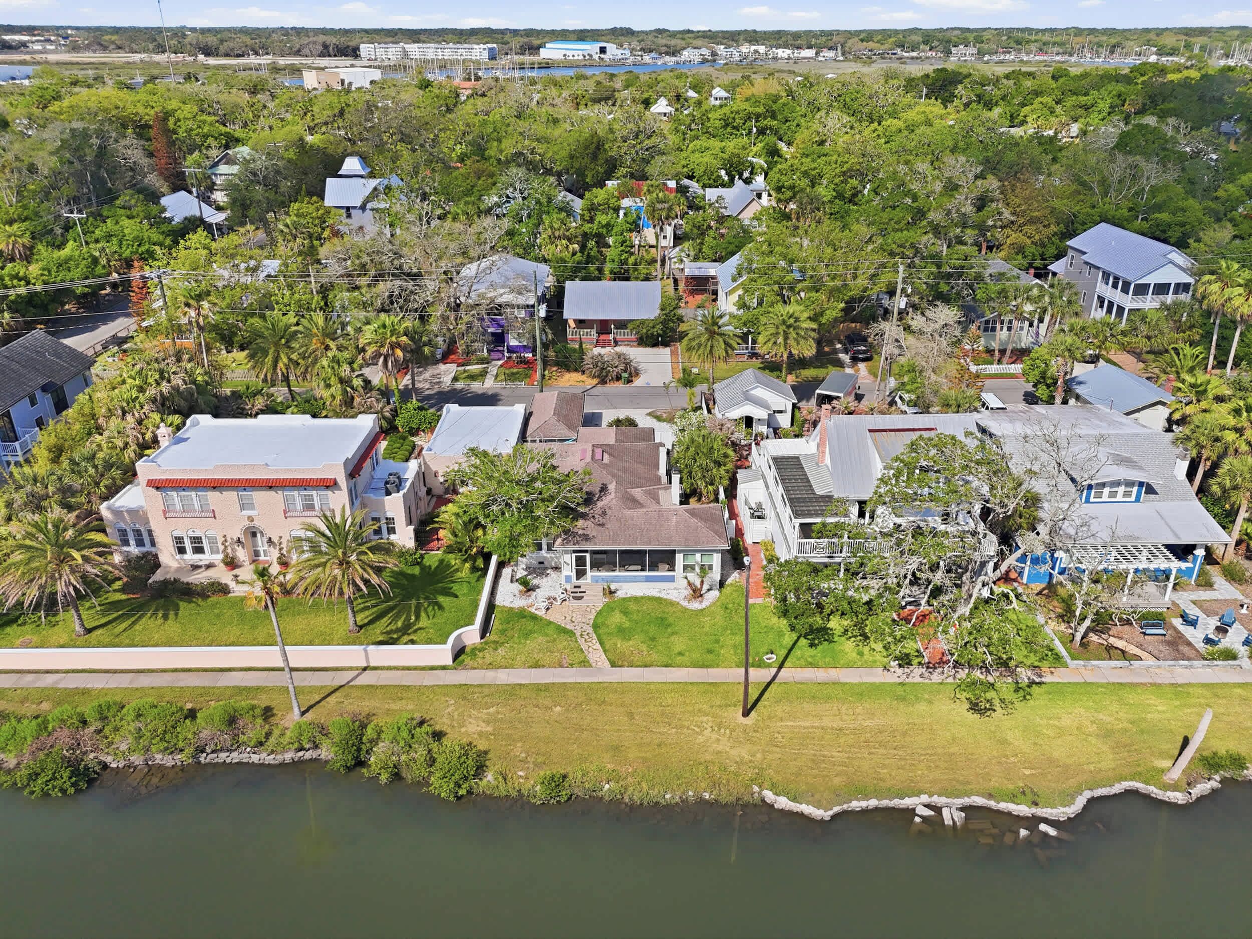 Vue aérienne d’un quartier résidentiel avec des maisons, un lac et une côte lointaine.