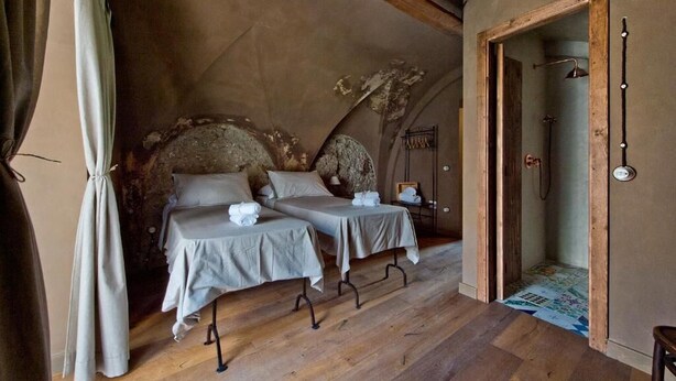 A room with two beds, a wooden floor, and a door leading to a bathroom. - una volta antica dimora del 1500 B&B (Cava de' Tirreni)