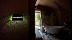 A room with a bathtub, a window with curtains, and a wall with a sign. - una volta antica dimora del 1500 B&B (Cava de' Tirreni)