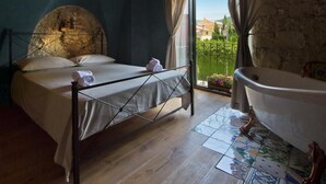 A bedroom with a bed, a bathtub, and a view of the outside. - una volta antica dimora del 1500 B&B (Cava de' Tirreni)