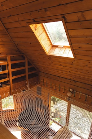 A wooden interior with a skylight, a mesh enclosure, and a staircase.