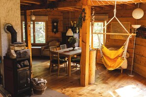 A rustic wooden interior with a dining area, a hammock, and a fireplace. - Bukowica Miła - Nature Escape with eco sauna (Wola Piotrowa)