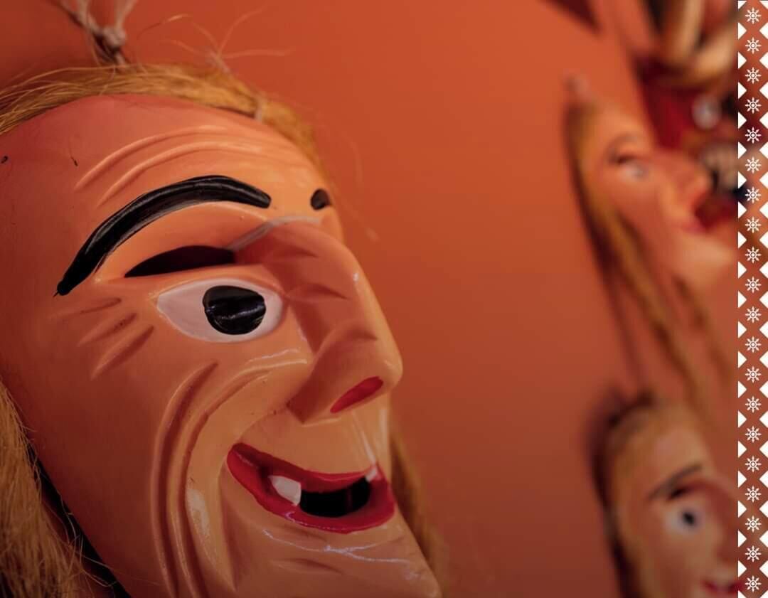 A close-up of a person wearing a mask with exaggerated facial features.