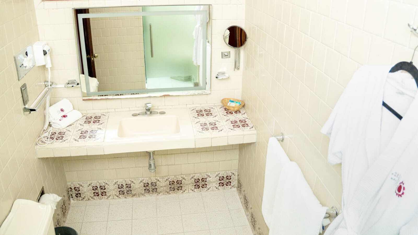 A bathroom with a sink, mirror, towel rack, and a small shelf with toiletries.