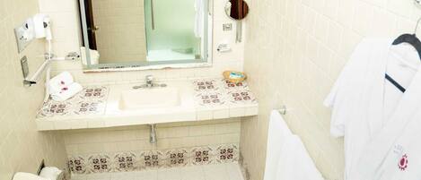 A bathroom with a sink, mirror, towel rack, and a small shelf with toiletries.