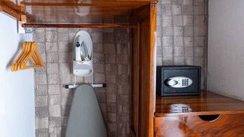 A corner of a room with a wooden ironing board, an iron, and a safe.