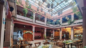A spacious atrium with multiple levels, wooden furniture, and hanging baskets. - Hotel Posada del Balsas  (Apatzingan)