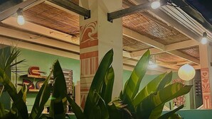 A building with a thatched roof, a green wall with a red and white design, and large green plants in the foreground. - La Casita - Glamping bungalow with AC in Rincón (Rincón)