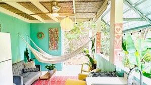 A compact kitchen with a sink, a dining area with a table and chairs, a hammock, and a sofa. - La Casita - Glamping bungalow with AC in Rincón (Rincón)