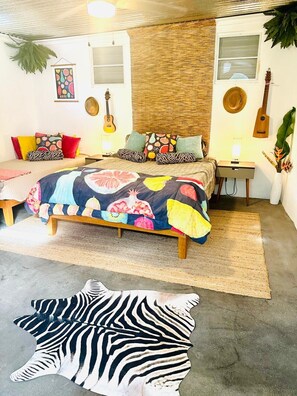 Een slaapkamer met een bed, een gitaar, een lamp en een plant.