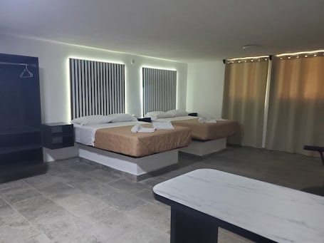 A hotel room with two beds, a bedside table, a TV, and a curtain.