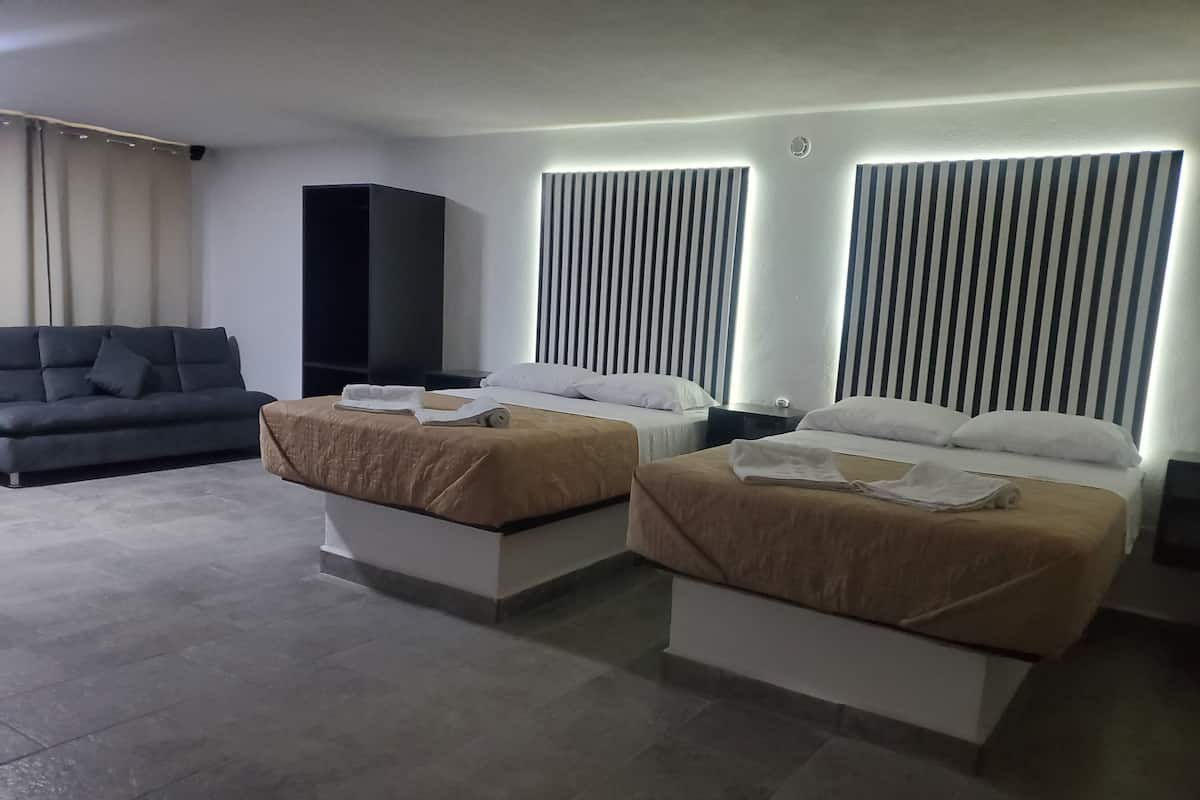 A hotel room with two beds, a sofa, a TV, and a wall with vertical lines.