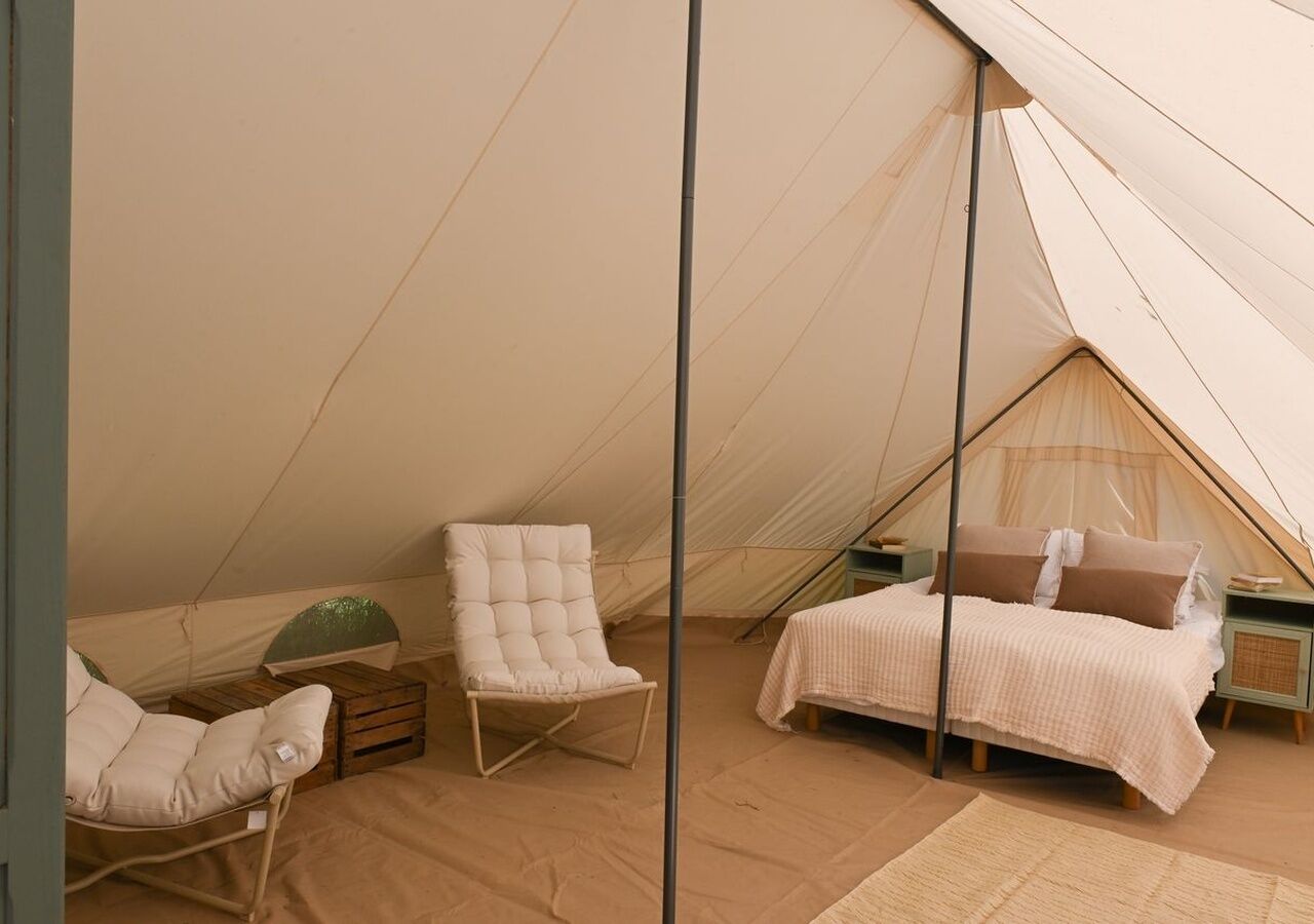 Una carpa con cama, una silla acolchada y una mesita.
