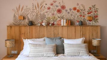 Une chambre à coucher avec une tête de lit en bois, un lit avec une literie à rayures, deux lampes de chevet et une fresque florale sur le mur.