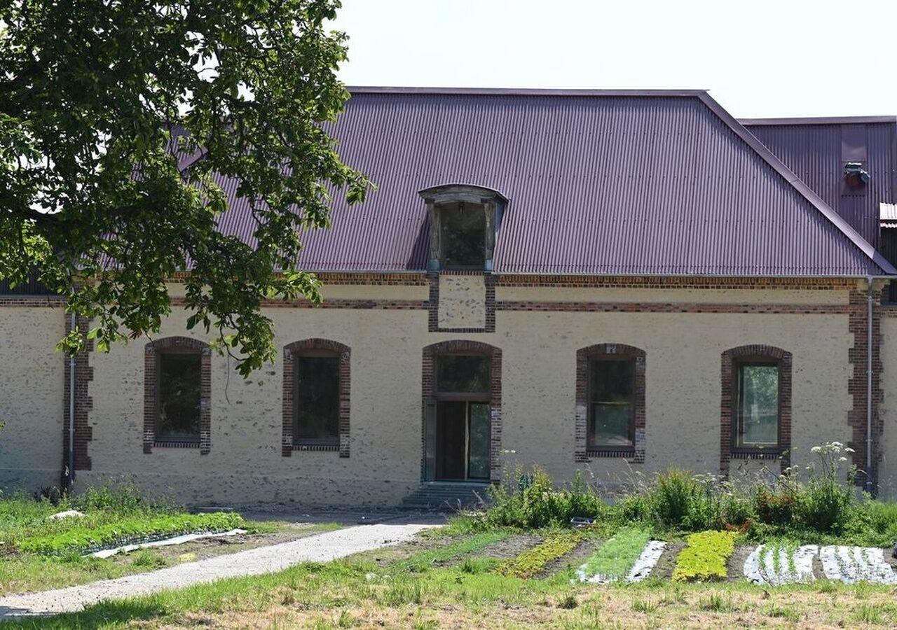 A building with a brick facade, a central entrance, and a metal roof.